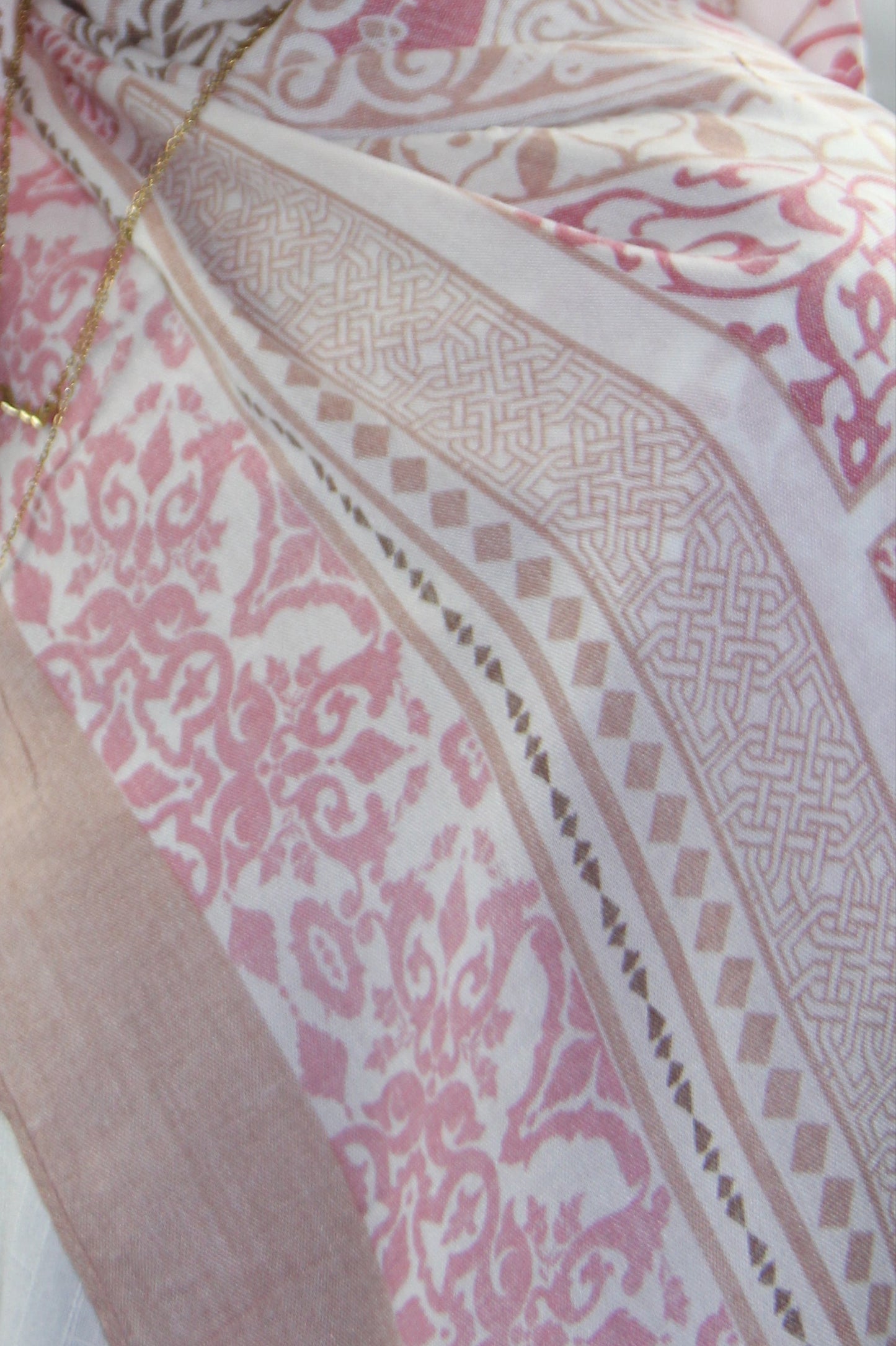 Woman wearing a pink hijab with intricate patterns on a white background