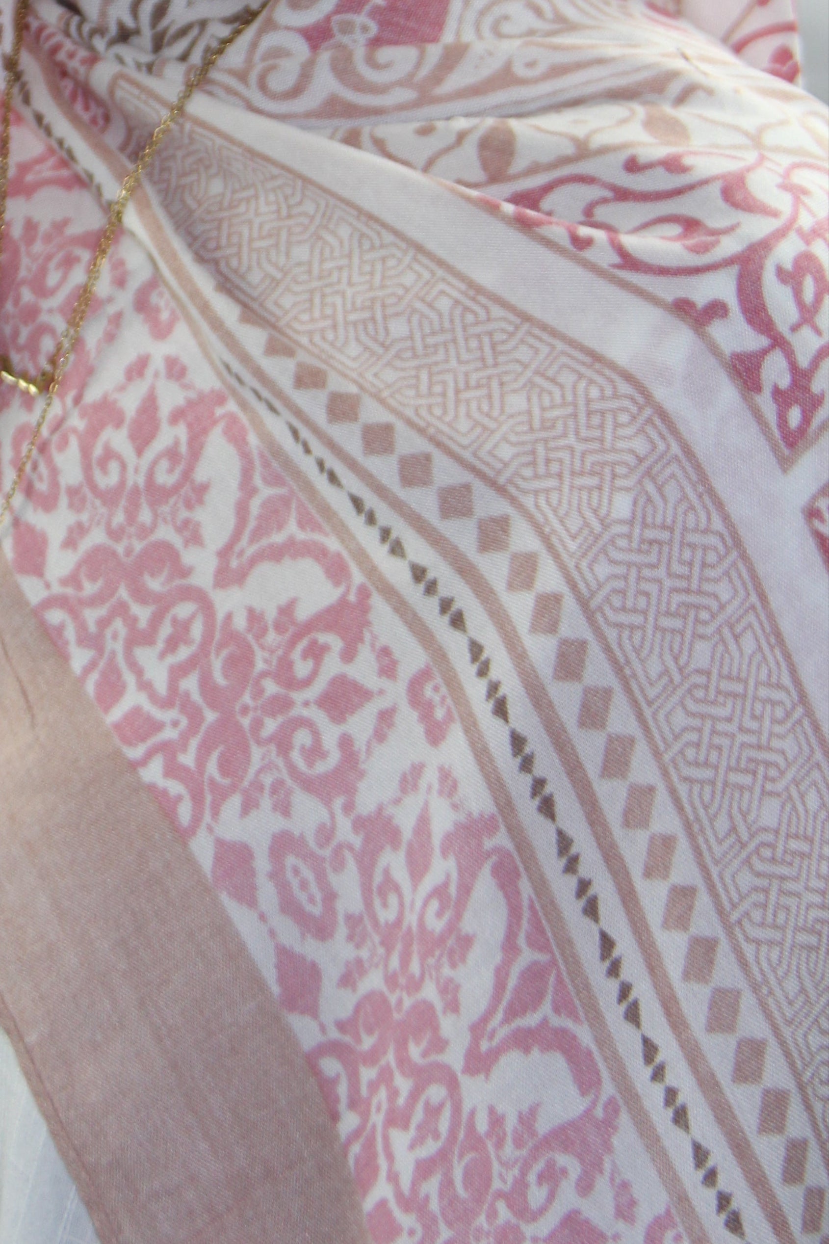 Woman wearing a pink hijab with intricate patterns on a white background